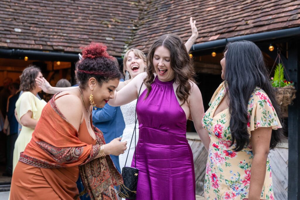 A group of women laughing and dancing together at an outdoor gathering, expressing happiness and enjoyment.