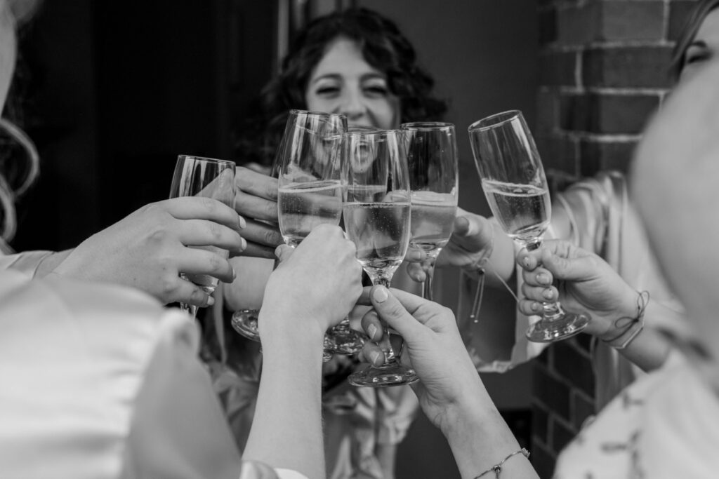 A group of people clinking champagne glasses in a toast, captured in black and white.