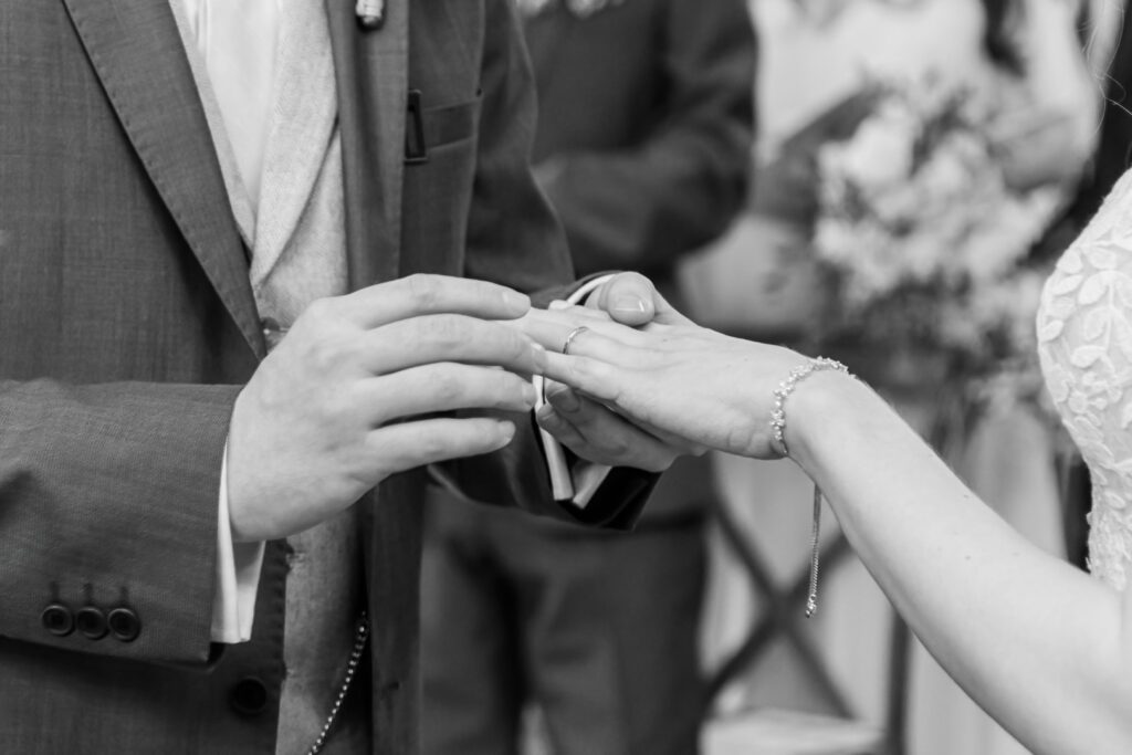 Close-up of a bride and groom's hands as they exchange wedding rings during a ceremony.