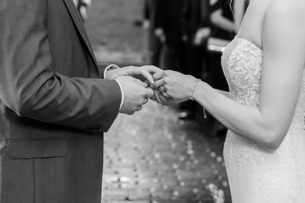 Close-up black and white photo of a bride and groom exchanging rings during a wedding ceremony