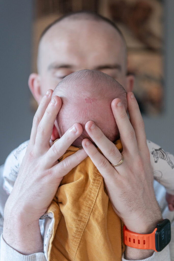 A parent gently cradles their baby's head while holding them close, showcasing an intimate connection.