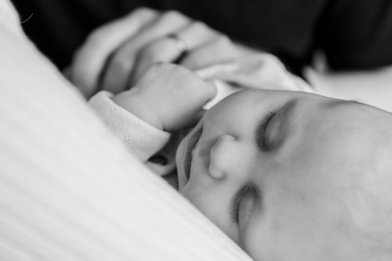 A close-up of a peacefully sleeping baby, with closed eyes and a relaxed expression, nestled against soft fabric.